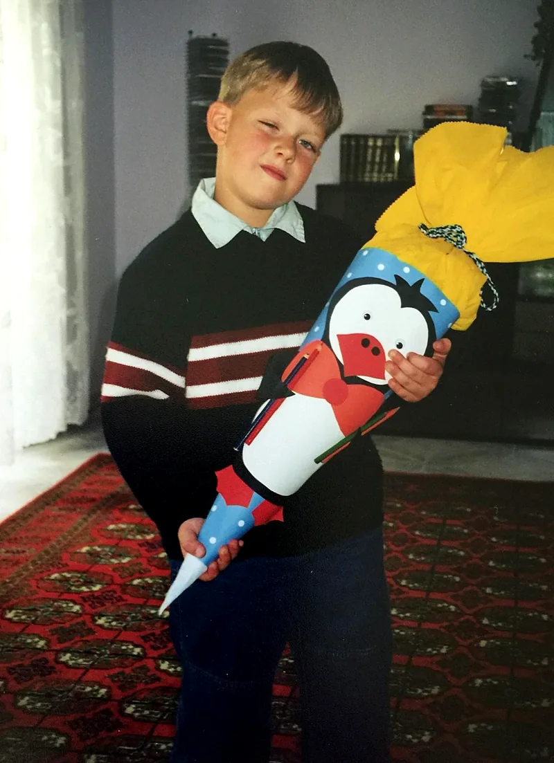 Arnold as a young boy on his first day of school, holding a big school cone