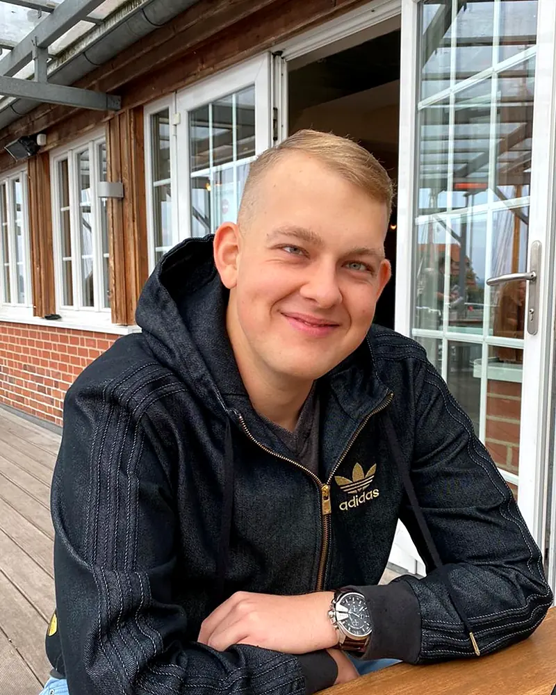 Arnold smiling at a wooden table outside a café