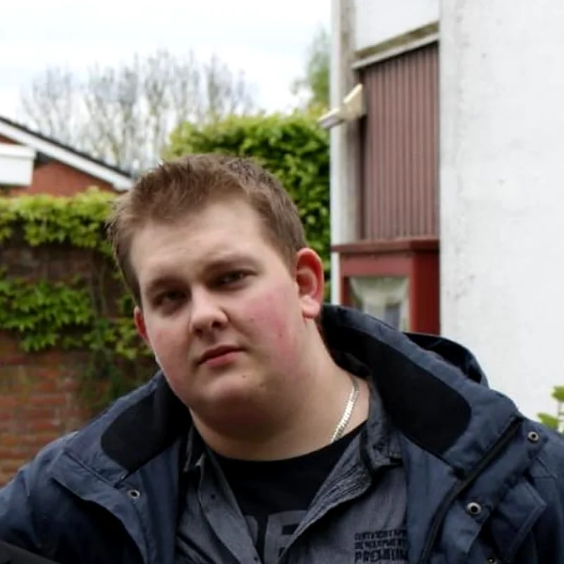 Arnold as a young man in a dark jacket in front of a house